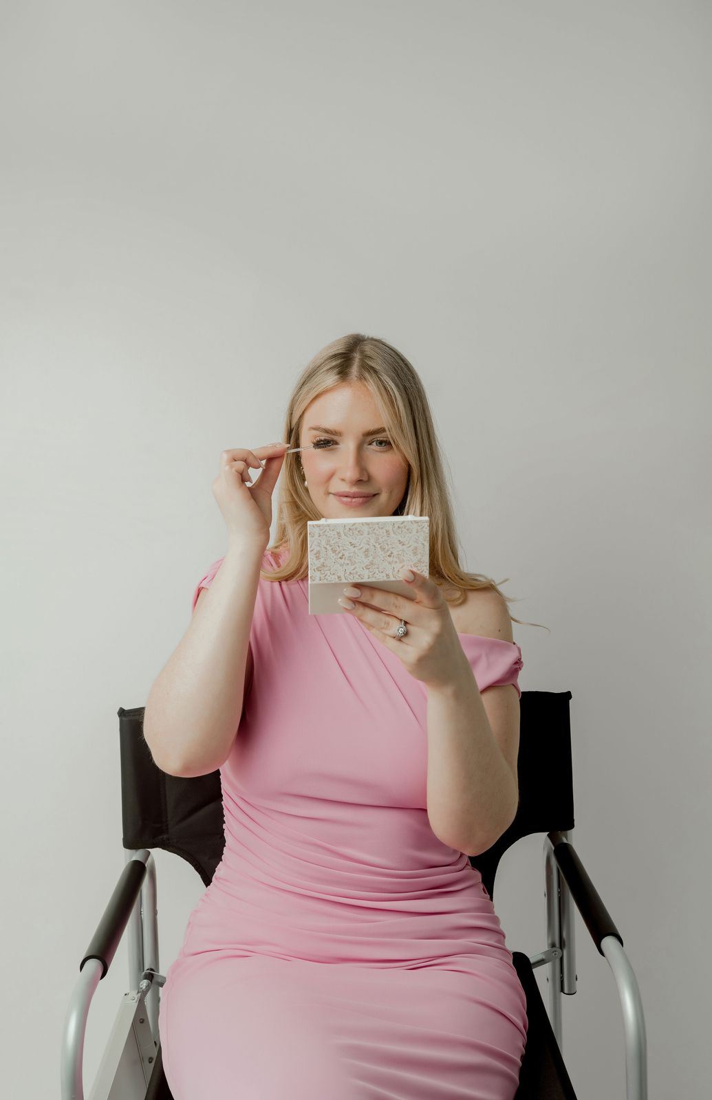Lindsey Heilman brushing her lashes with a compact mirror